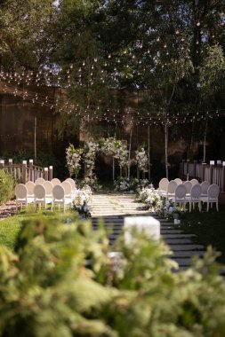 Wedding ceremony. Very beautiful and stylish wedding arch, decorated with various fresh flowers, standing in the garden. Wedding day. Fresh flowers decorations. Wedding day.