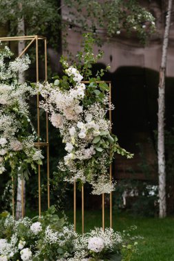Wedding ceremony. Very beautiful and stylish wedding arch, decorated with various fresh flowers, standing in the garden. Wedding day. Fresh flowers decorations. Wedding day.