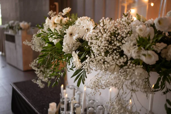 Main table at a wedding reception with beautiful fresh flowers. Wedding day. Fresh flowers arrangements. Wedding with candles and bubble lights.