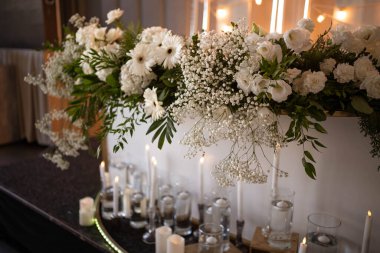 Main table at a wedding reception with beautiful fresh flowers. Wedding day. Fresh flowers arrangements. Wedding with candles and bubble lights.