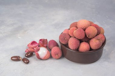Lychee exotic fruits in bowl. Fresh Longan tropical fruit in Thailand. gray stone backgroud.