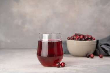 Açık gri arka planda sağlıklı kızılcık suyu olan bir bardak. Biyolojik meyve suyu.