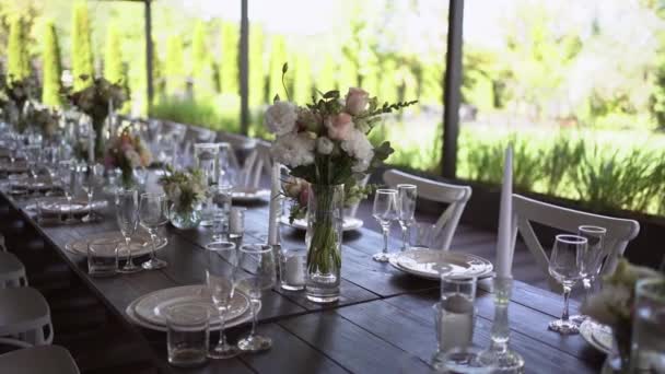 春の庭でプレートやサービットと美しい装飾が施された非常によく装飾された結婚式のテーブルの予定 結婚式の日にテーブルの上の美しい花 エレガントなディナーテーブル 結婚式日 — ストック動画