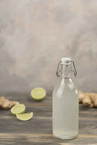 stock image Bottle with homemade ginger ale, lemon and gingerroot on gray background. Front view.