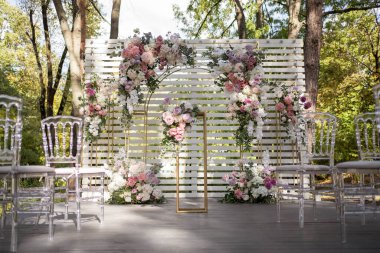 Wedding ceremony. Very beautiful and stylish wedding arch, decorated with various flowers, standing in the garden. Wedding day.