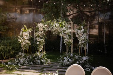Wedding ceremony. Very beautiful and stylish wedding arch, decorated with various fresh flowers, standing in the garden. Wedding day. Fresh flowers decorations. Wedding day.