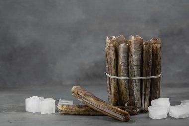 Bunch of clams razor on the gray stone background. Close up of fresh seafood. Ice, lemon and fresh seafood.