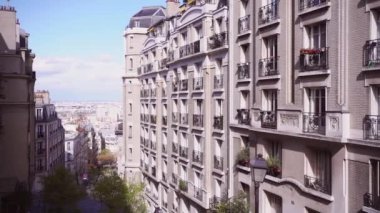 Paris 'in merkezinde eski binalar, çiçek açan ağaçlarla dolu bir sokak. Ağır çekim. Panoramik görünüm.
