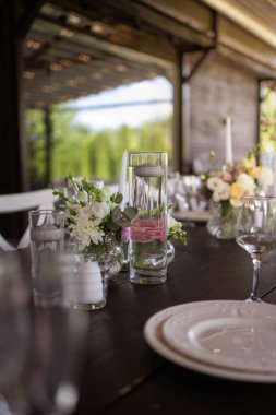 Çok güzel dekore edilmiş bir düğün masası randevusu. Baharın bahçesinde tabaklar ve peçetelerle süslenmiş güzel bir dekor. Düğün günü masada güzel çiçekler. Zarif yemek masası. Düğün günü.