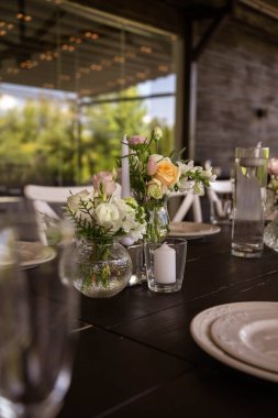 Çok güzel dekore edilmiş bir düğün masası randevusu. Baharın bahçesinde tabaklar ve peçetelerle süslenmiş güzel bir dekor. Düğün günü masada güzel çiçekler. Zarif yemek masası. Düğün günü.