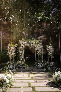 Wedding ceremony. Very beautiful and stylish wedding arch, decorated with various fresh flowers, standing in the garden. Wedding day. Fresh flowers decorations. Wedding day.