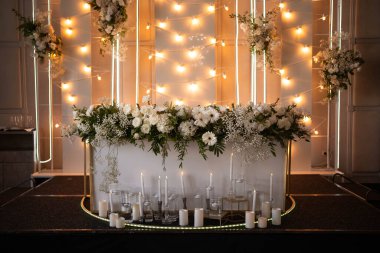 Main table at a wedding reception with beautiful fresh flowers. Wedding day. Fresh flowers arrangements. Wedding with candles and bubble lights.