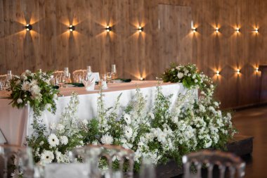 Main table at a wedding reception with beautiful fresh flowers. Wedding day. Fresh flowers arrangements. Wedding with candles and bubble lights.