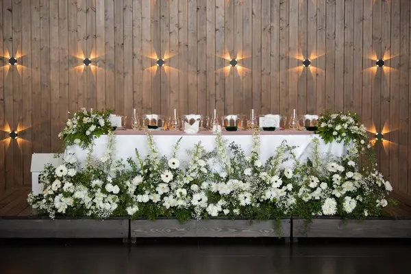 Main table at a wedding reception with beautiful fresh flowers. Wedding day. Fresh flowers arrangements. Wedding with candles and bubble lights.