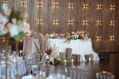Main table at a wedding reception with beautiful fresh flowers. Wedding day. Fresh flowers arrangements. Wedding with candles and bubble lights.