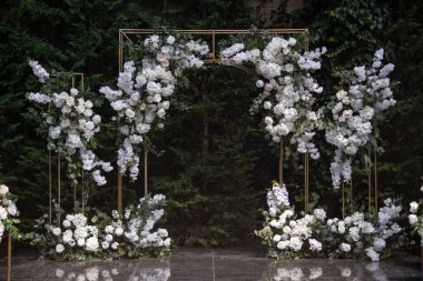 Wedding ceremony. Very beautiful and stylish wedding arch, decorated with various fresh flowers, standing in the garden. Wedding day. Fresh flowers decorations. Wedding day.