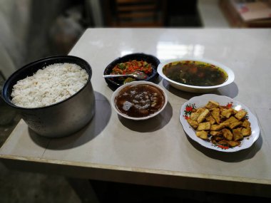 Bir tabak pilav, bir kase çorba, bir tabak kızarmış tofu ve bir tabak baharatlı sos..