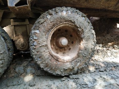 Ağır makinelerde çamurlu bir lastiğin yakın çekimi, tekerleğin etrafında ve kenarında kalın çamurlar olması, ıslak koşullarda off-road kullanımını gösteriyor..