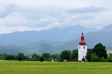 Tatra dağlarının arka planındaki kilise beyaz kulesi. Bulutlu ve yağmurlu bir günde