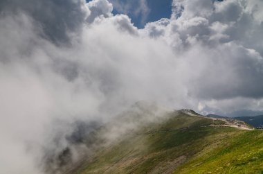 Bir dağ yolu bulutlara karışıyor. Yüksek dağlarda gevşeme.