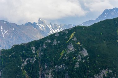 Tatra Ulusal Parkı 'nın zirveleri. Morskie Oko 'dan Five Pond vadisine giden mavi turist patikasından görüntü. Tepelerin üzerinde resim gibi bulutlar.