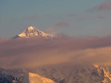 Kışın dağların manzarası. Tatra Ulusal Parkı - Czarna Gora 'dan. Dağ zirveleri, bulutların arasından parlayan batan güneşin ışınlarıyla aydınlanır. Spisz. Malopolskie. Polonya.