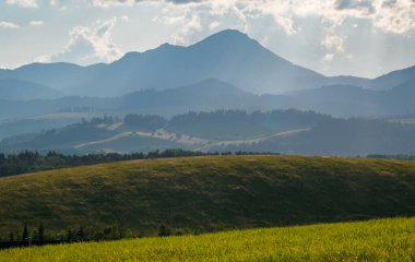 Dağ manzarası. Batan güneş tepelerin yamaçlarını aydınlatır. Hoczanskie Dağları manzarası. Zilina Bölgesi. Slovakya.