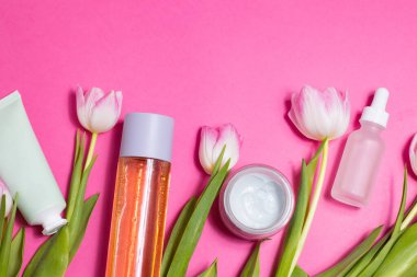 Beauty background with natural cosmetic, green leaves and flowers. Flat lay image on blue. High quality photo