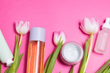 Beauty background with natural cosmetic, green leaves and flowers. Flat lay image on blue. High quality photo