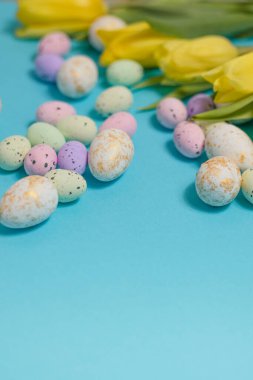 Yellow tulip flowers and easter eggs on blue background. Top view with copy space. Happy easter greeting card. High quality photo