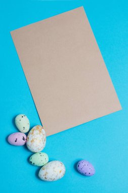 Layout of colorful easter eggs and card on a blue background. Holiday concept with place for text.High quality photo