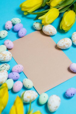 Yellow tulip flowers and easter eggs on blue background. Top view with copy space. Happy easter greeting card. High quality photo
