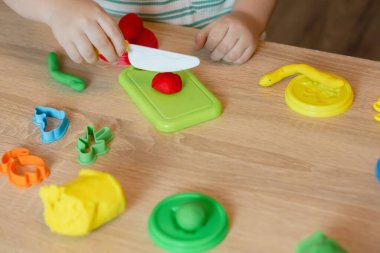 Evde oynayan sevimli küçük bir çocuk, çok renkli plastik kalıplar çıkarıyor. Kil kaplamalı bebek heykelleri. Hamur oyna