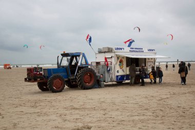 Soğuk bir günde deniz kıyısında fast food römorku olan traktör.