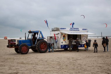 Soğuk bir günde deniz kıyısında fast food römorku olan traktör.