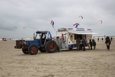 Soğuk bir günde deniz kıyısında fast food römorku olan traktör.
