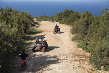 İnsanlar dağlarda dörtlü arabalara biniyor.