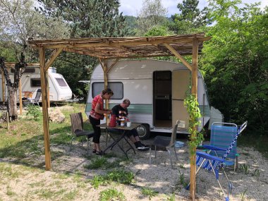 Turistler kamp alanında çadırın altında öğle yemeği yiyorlar.