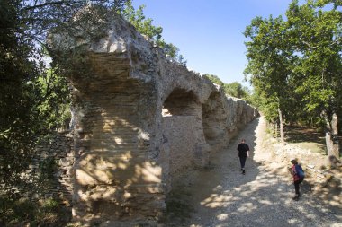 Turistler Güney Fransa 'daki antik Roma Pont du Gard su kemeri yakınlarında yürüyorlar..