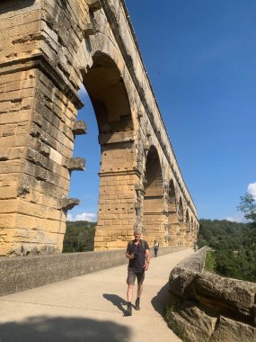 Kameralı turist Güney Fransa 'da Roma Pont du Gard köprüsü boyunca yürüyor. 