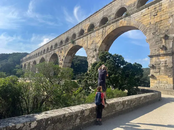 Turistler Güney Fransa 'daki antik Roma Pont du Gard su kemeri yakınlarında yürüyorlar..