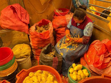 Peru - 30 Aralık 2023: Yerel pazarda patates soyan kadın.