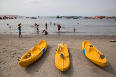 Paracas, Peru - 27 Aralık 2023: Sarı kanolar ve deniz kıyısındaki insanlar