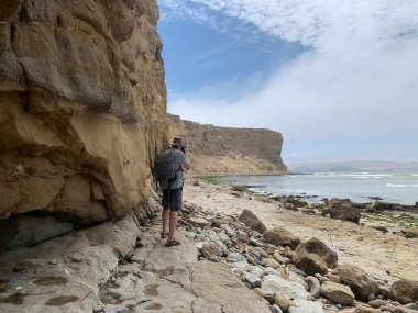 Sırt çantalı bir adam manzaranın fotoğraflarını çekiyor.