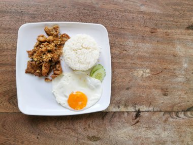 Moo tod kratiem ya da gratiem. Beyaz tabakta ahşap kaplama sarımsaklı ve biberli kızarmış domuz eti. Tayland 'da sokak yemeği.