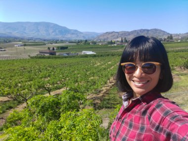 Kanada, British Columbia Okanagan Vadisi 'ndeki meyve bahçesindeki bir kadının selfie' si..