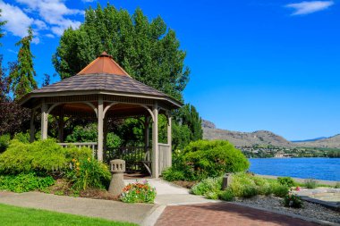 Okanagan Vadisi, Osoyoos, British Columbia, Kanada 'daki Osoyoos Gölü' nün kıyısındaki bir bahçe parkında ahşap bir çardak..