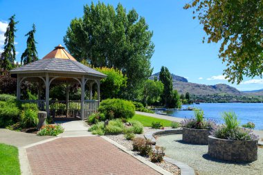 Okanagan Vadisi, Osoyoos, British Columbia, Kanada 'daki Osoyoos Gölü' nün kıyısındaki bir bahçe parkında ahşap bir çardak..