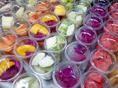 Bukit Bintang, Kuala Lumpur, Malezya 'daki Jalan Alor' da yerel bir sokak gıda pazarında meyve suyu yapmak için plastik bardaklarda kesilmiş tropik meyve çeşitleri..