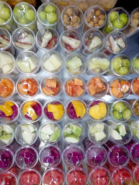 Bukit Bintang, Kuala Lumpur, Malezya 'daki Jalan Alor' da yerel bir sokak gıda pazarında meyve suyu yapmak için plastik bardaklarda kesilmiş tropik meyve çeşitleri..